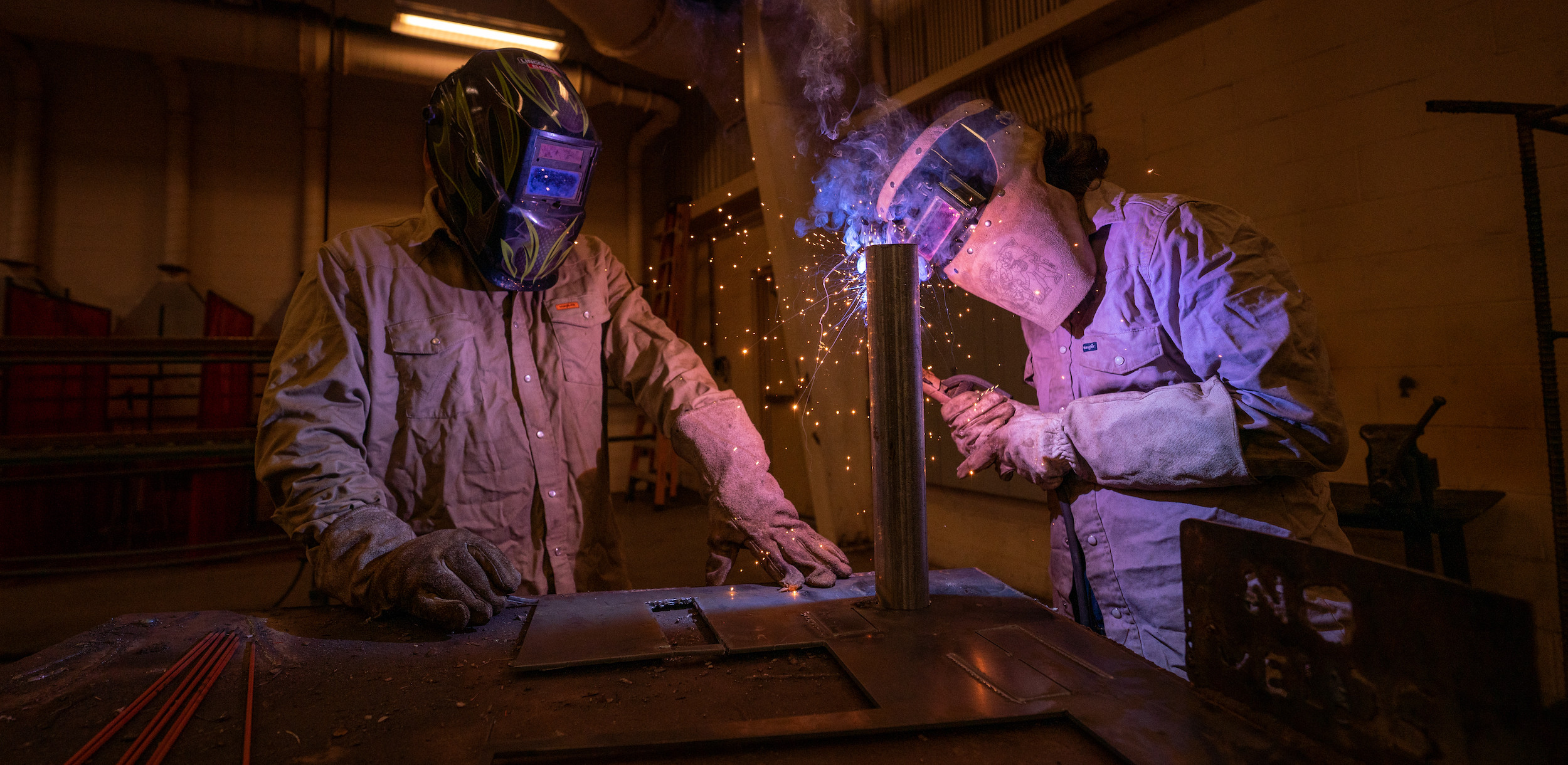 Two welders working on a piece of metal